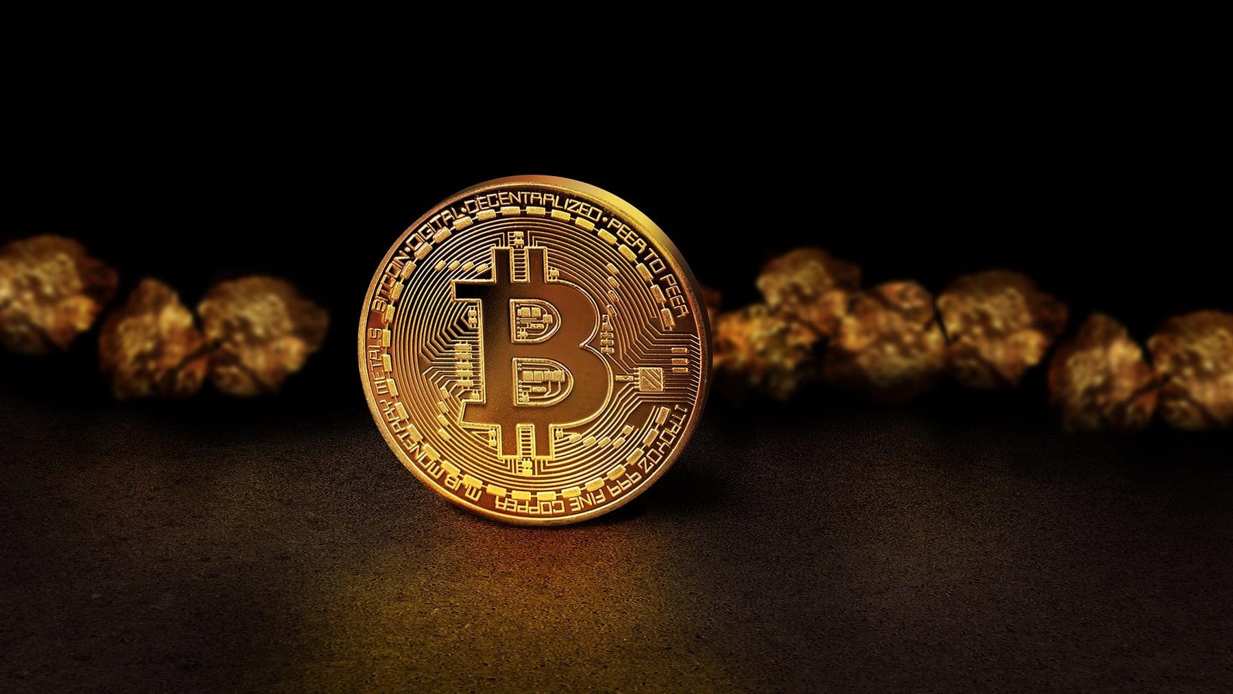 A golden bitcoin coin lying among raw gold nuggets on a dark background